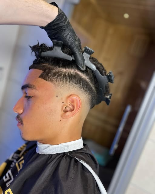 Een strakke fade met zorgvuldig afgewerkte contouren van Qui the Barber